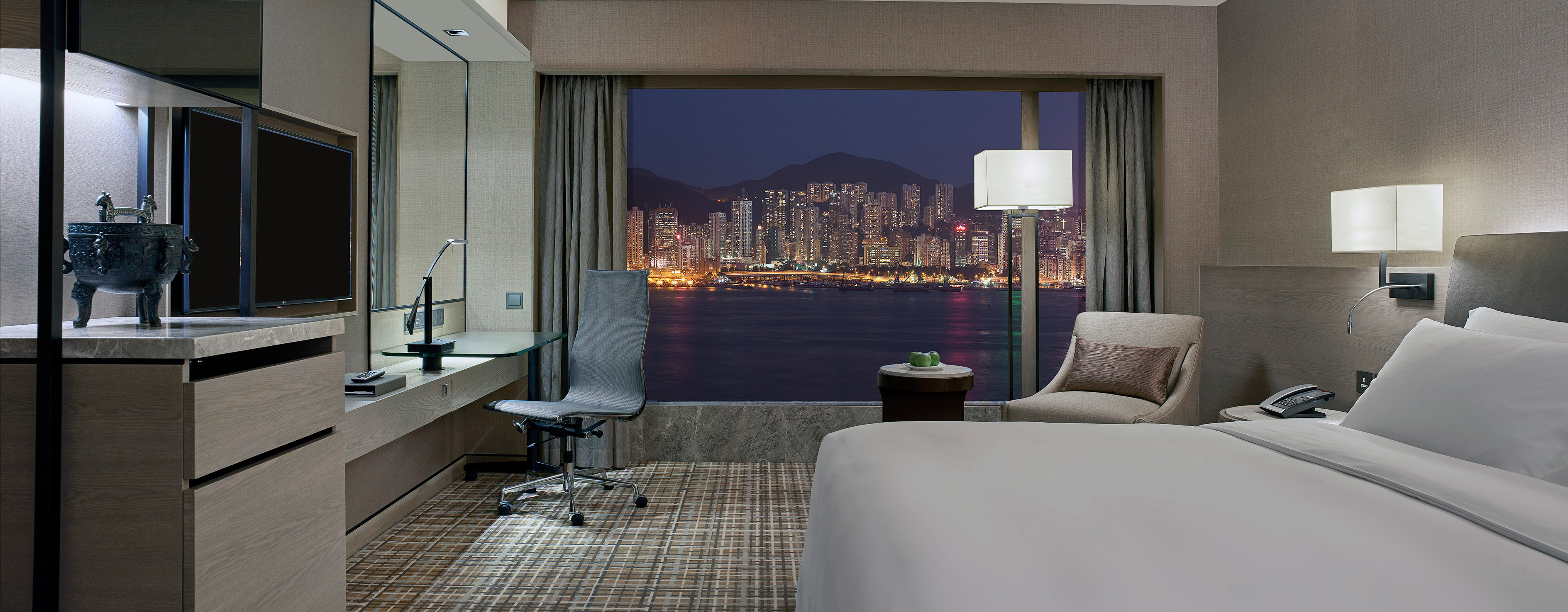 interior of the deluxe harbour view suite living room at the New World Millennium Hotel in Hong Kong showing a sofa across from a large flat screen television and large window